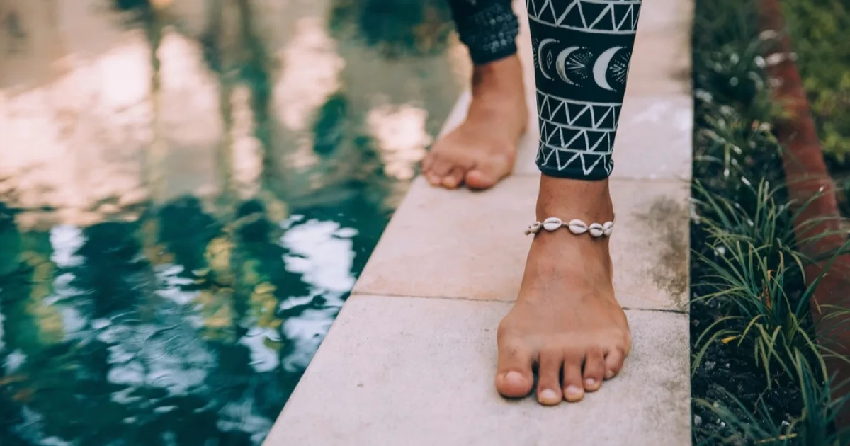 Adult walking barefoot beside a pool