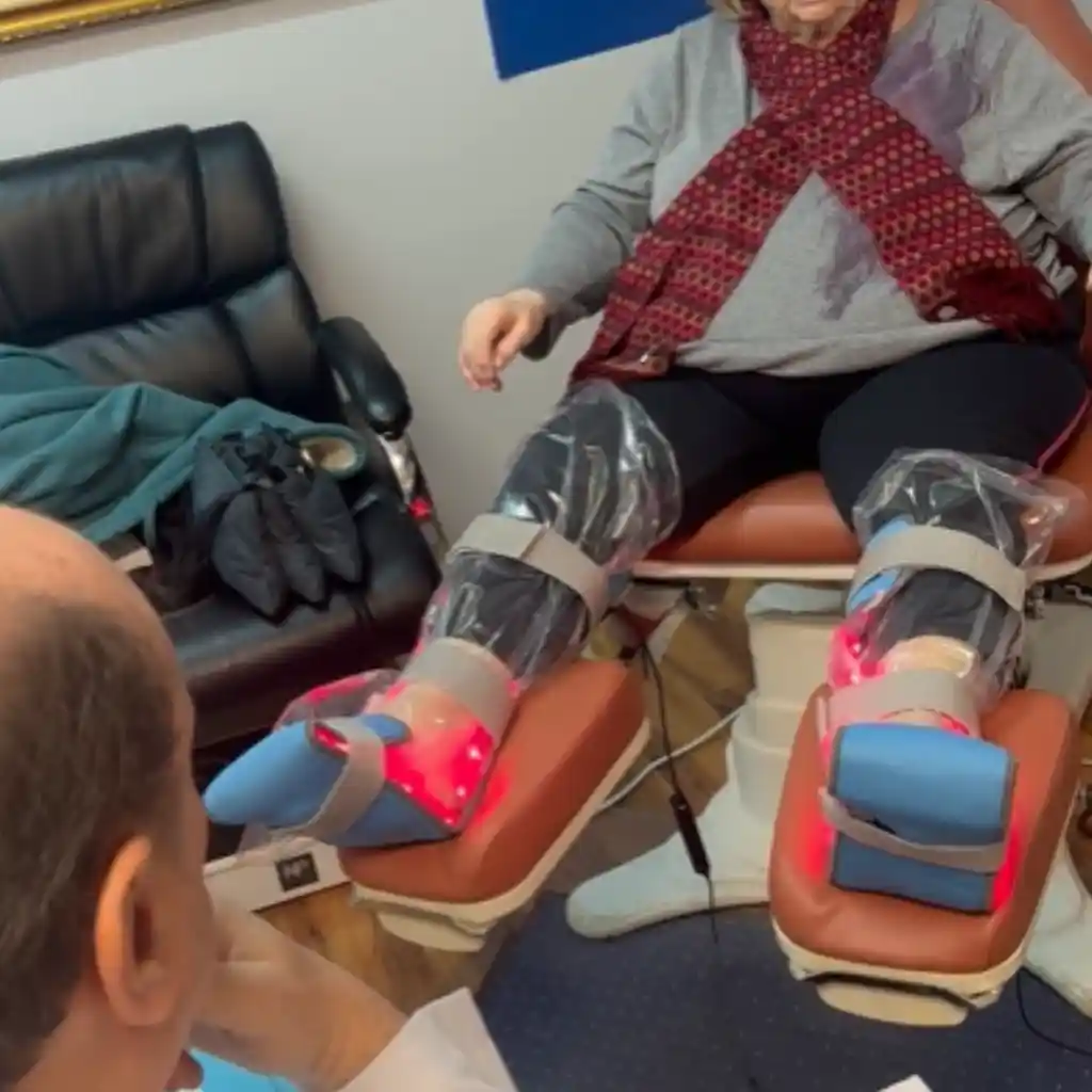 Patient receiving infrared light therapy on both feet during an in-office treatment