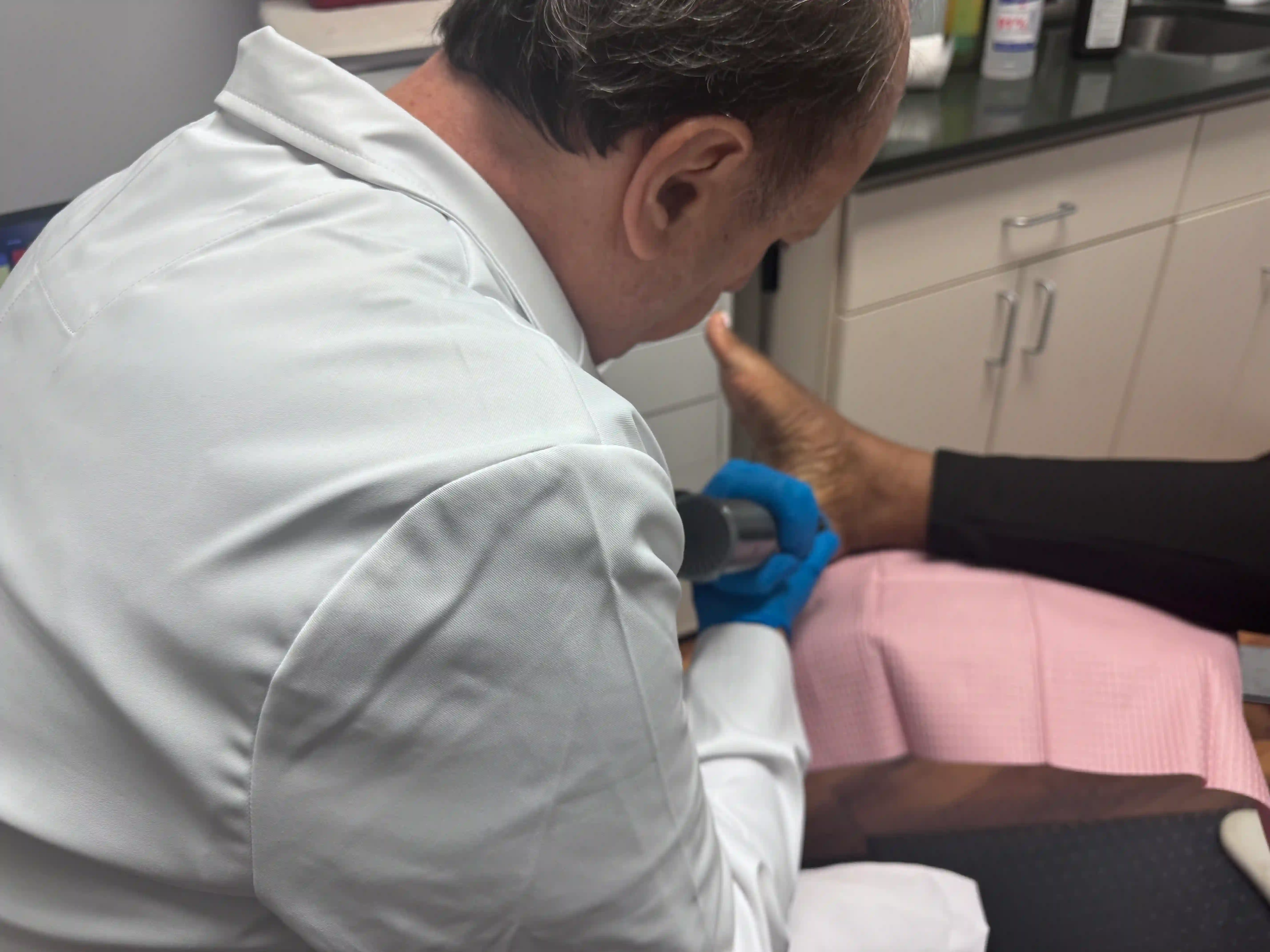 Dr. Sean Lazarus providing radial shockwave therapy during an in-office foot treatment